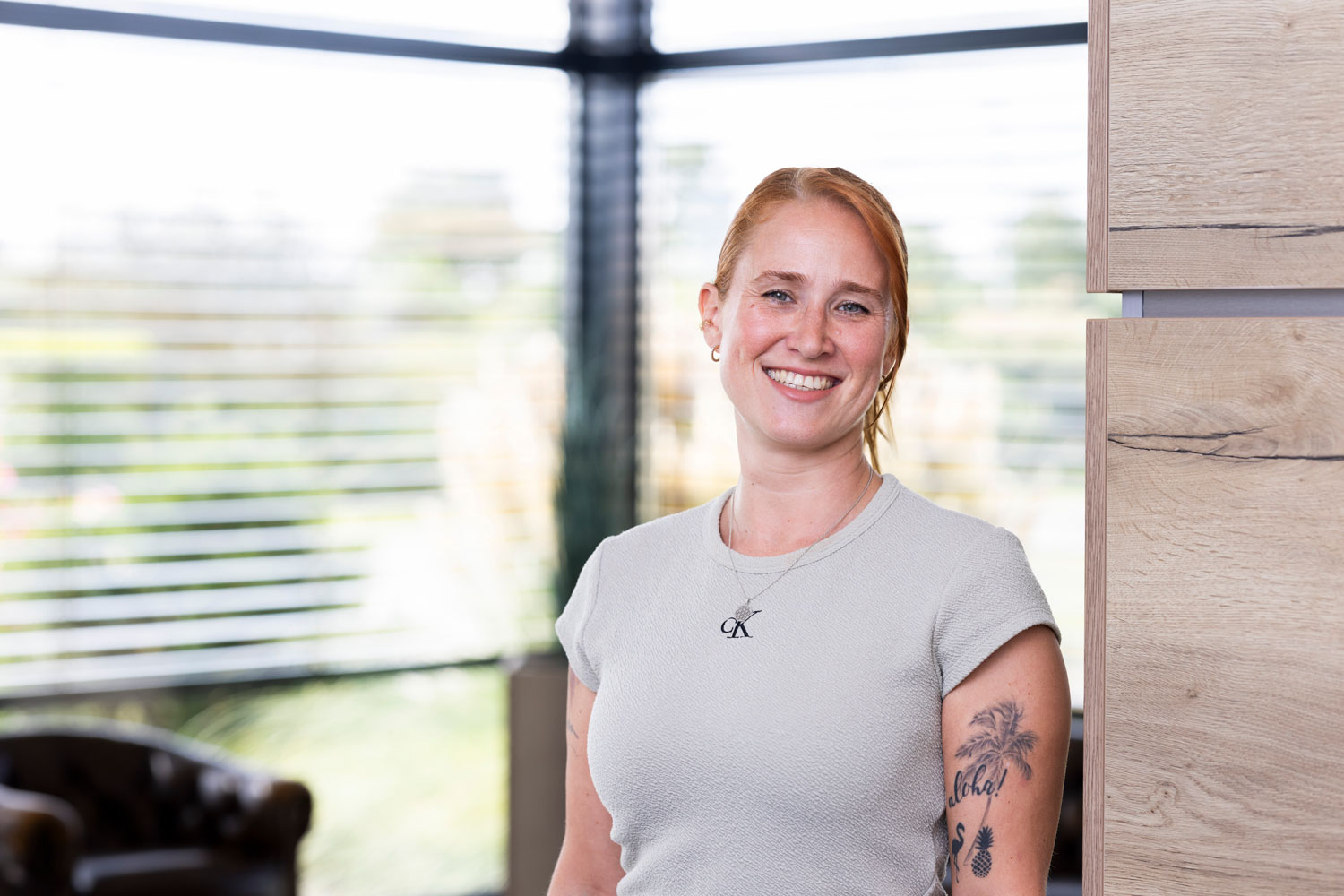 Freundliches Porträt einer Frau im Büro, natürliche Beleuchtung, modernes Arbeitsumfeld, Wohnquartier.