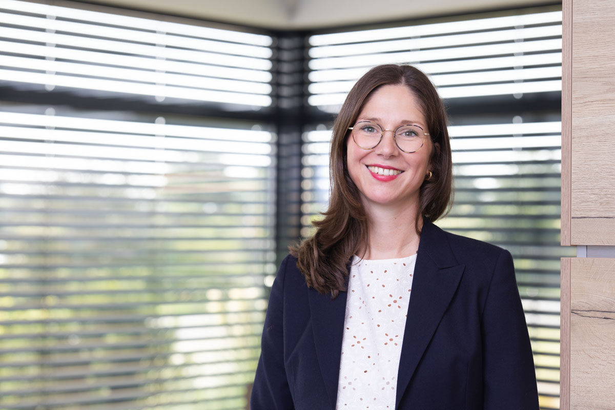 Freundliches Porträt einer Frau im Büro, natürliche Beleuchtung, modernes Arbeitsumfeld, Wohnquartier.