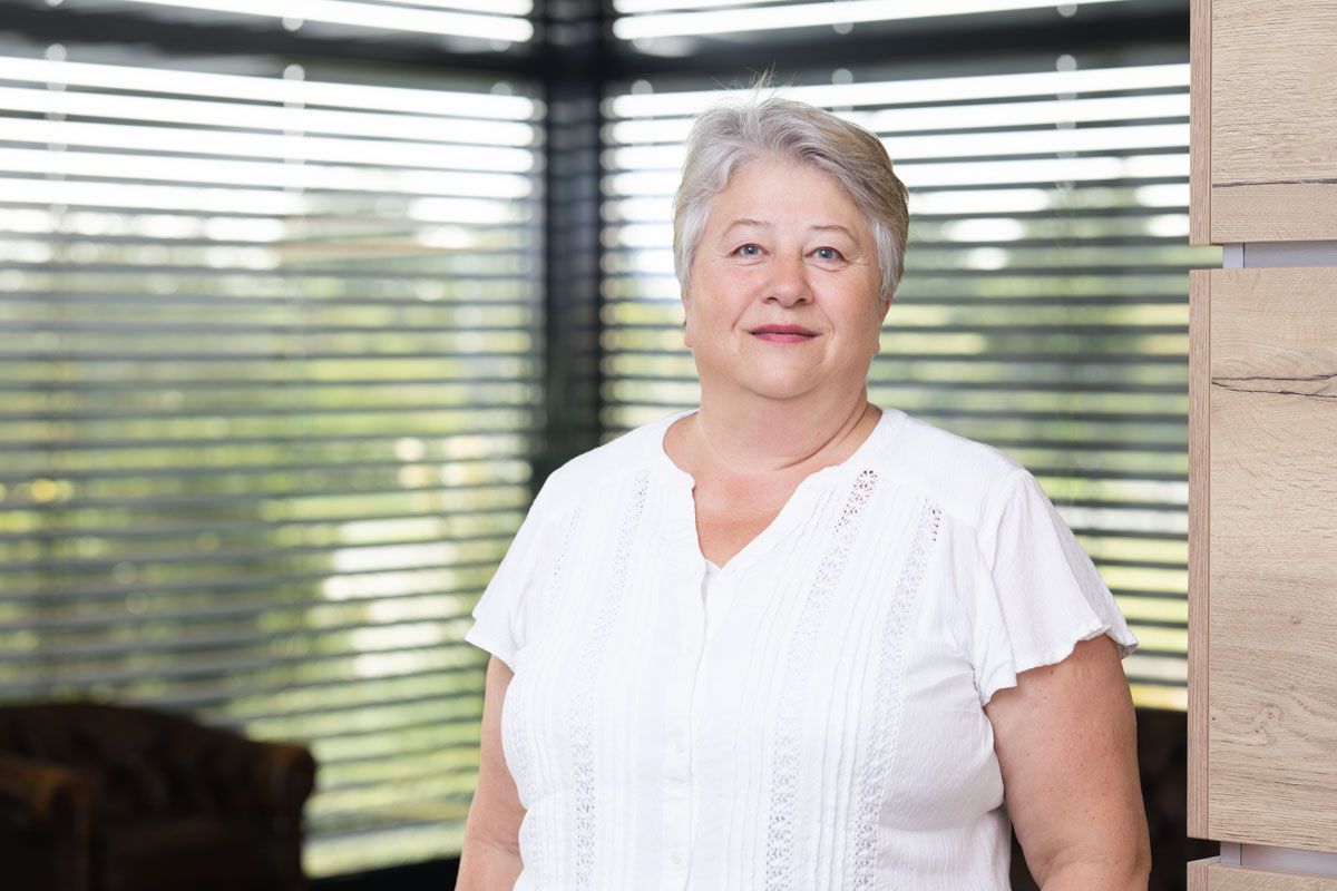 Freundliches Porträt einer Frau im Büro, natürliche Beleuchtung, modernes Arbeitsumfeld, Wohnquartier.